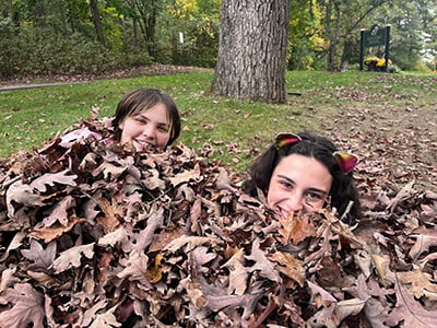 two students playing in leaves