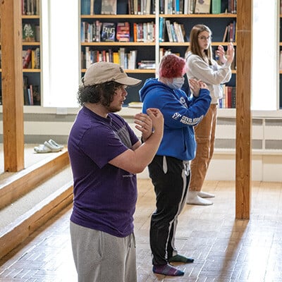 three people practicing tai-chi indoors