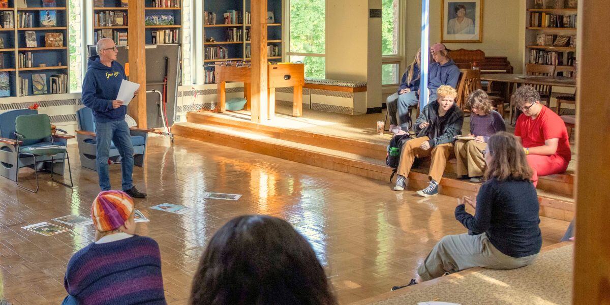 The Head of School at Rock Point School speaks in the library to a group of students during the weekly "Reflections" meeting.